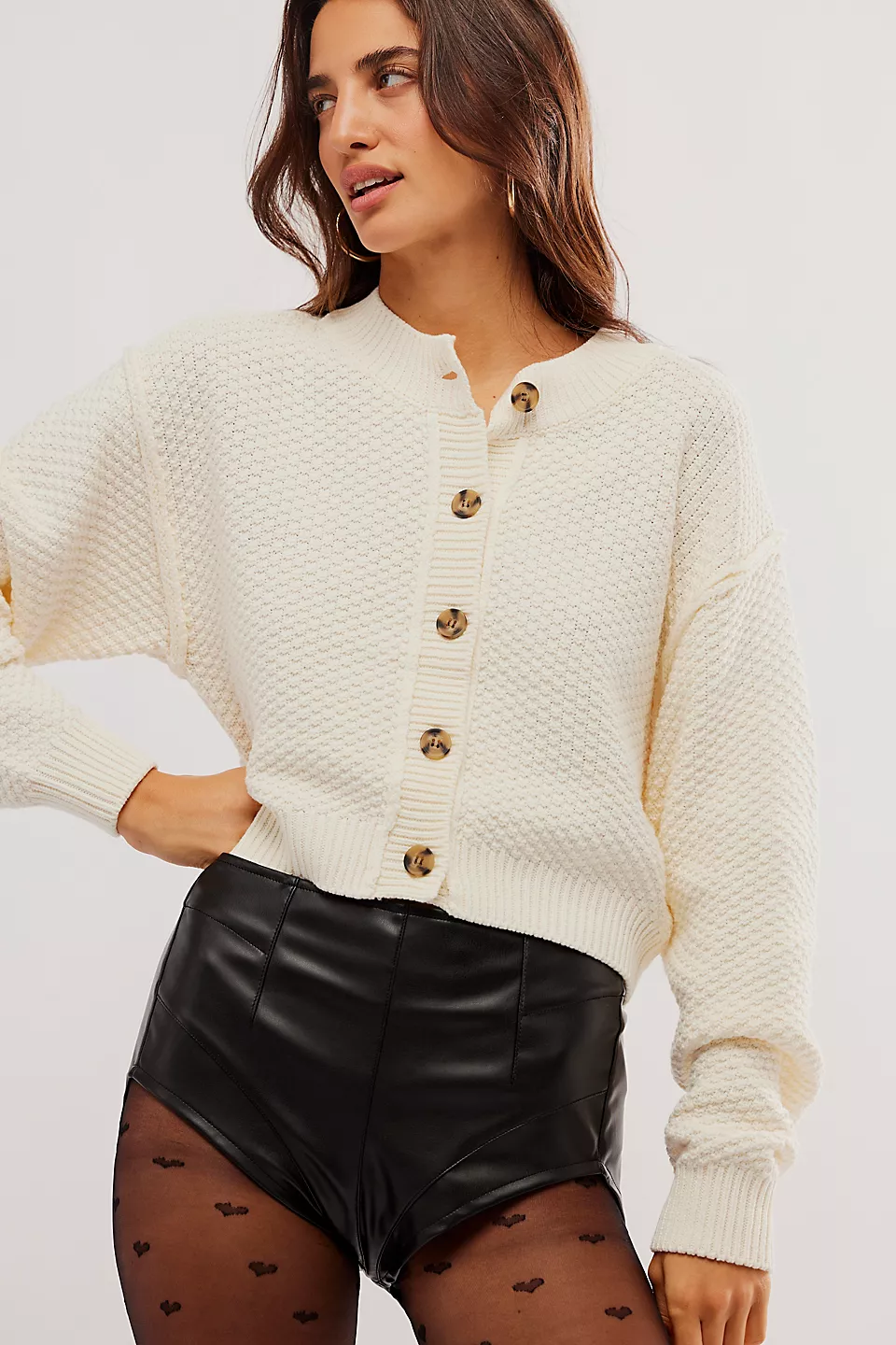 Cream cropped knit cardigan with leather mini shorts on model
