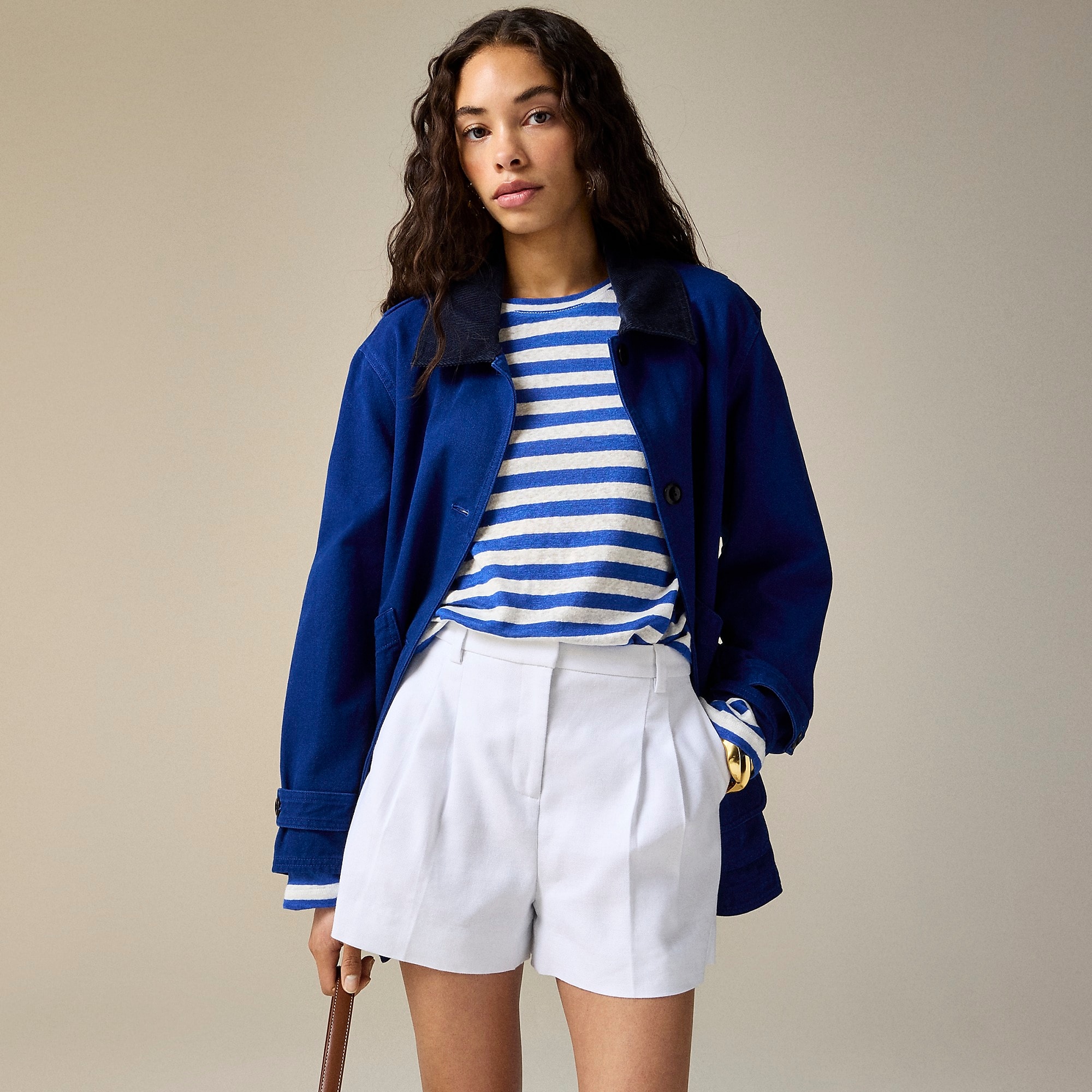 Tailored white shorts with a blue jacket and striped shirt on a model