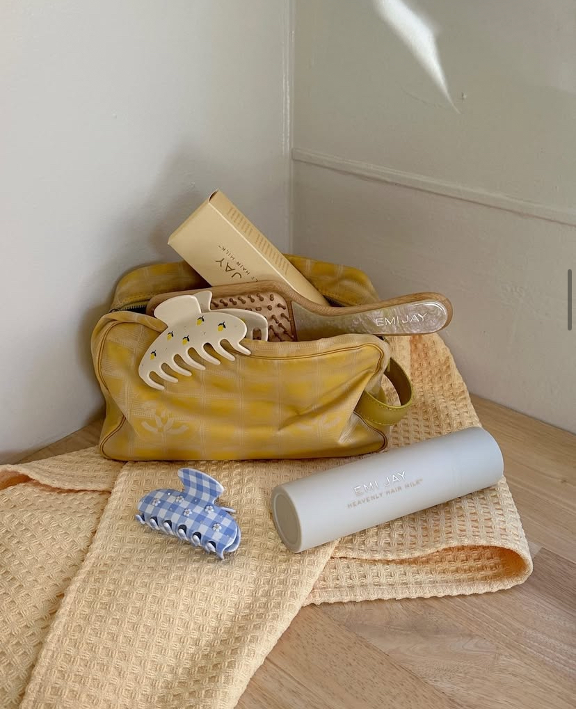Emi Jay accessories and products in and around a yellow case and towel