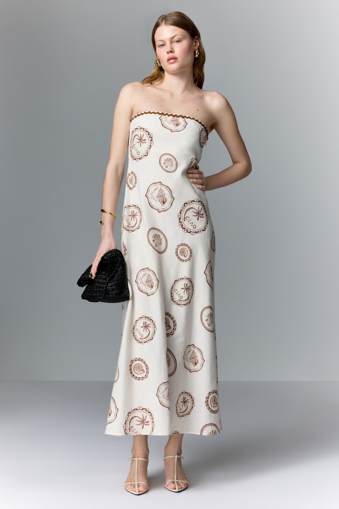 White silk strapless maxi dress with brown palm tree and "CIAO" circle designs on a model.
