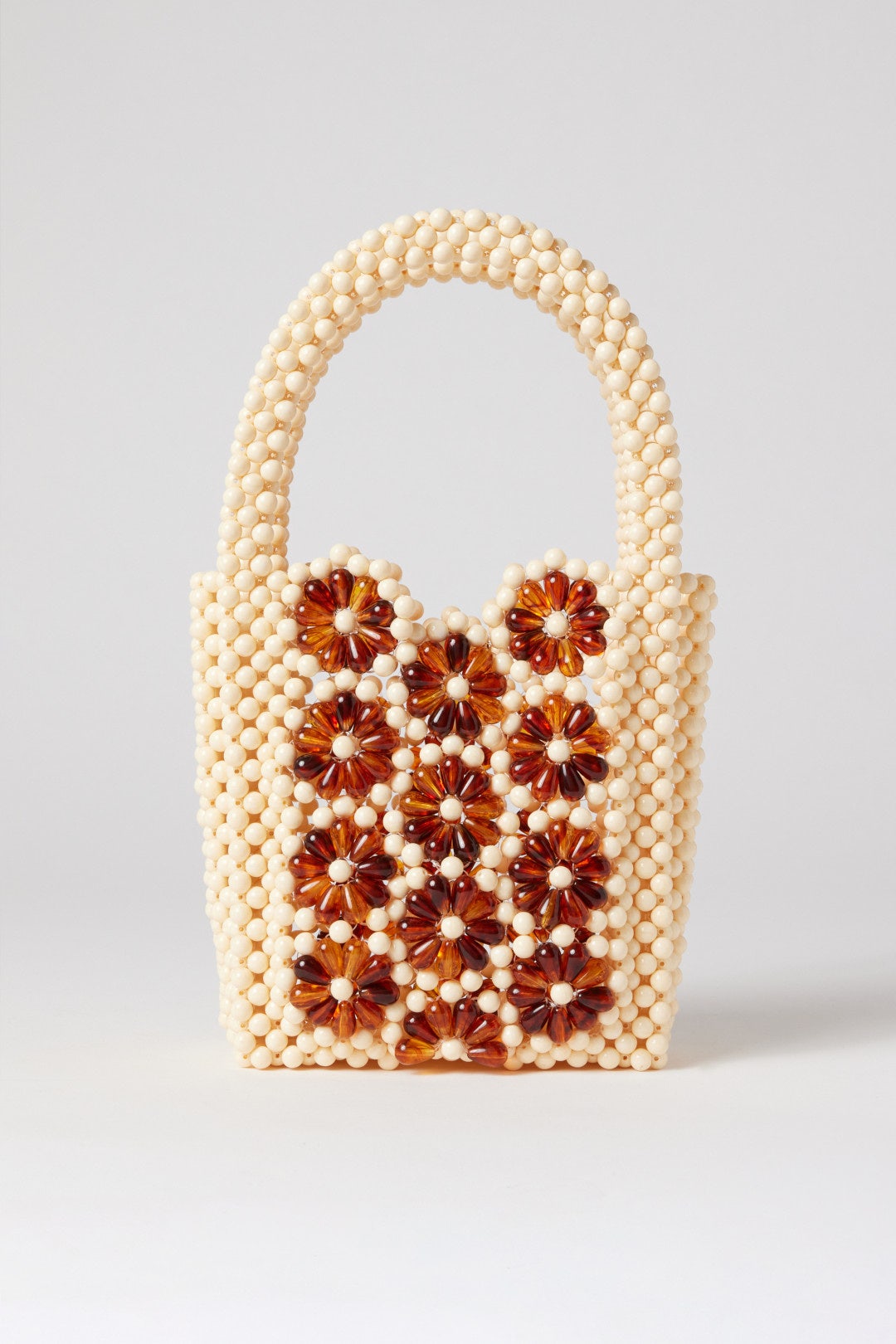 Cream beaded purse with shorts strap and tortoise shell flower details.