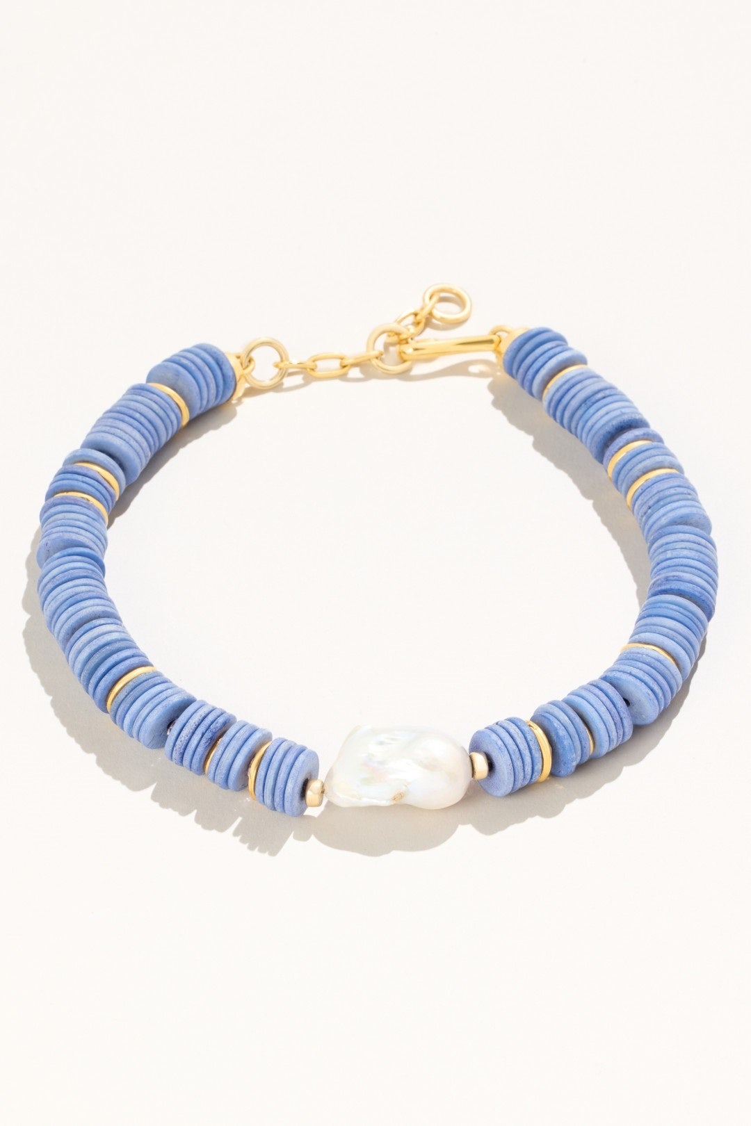 Blue disk beaded necklace with gold-tone accents and a singular pearl.