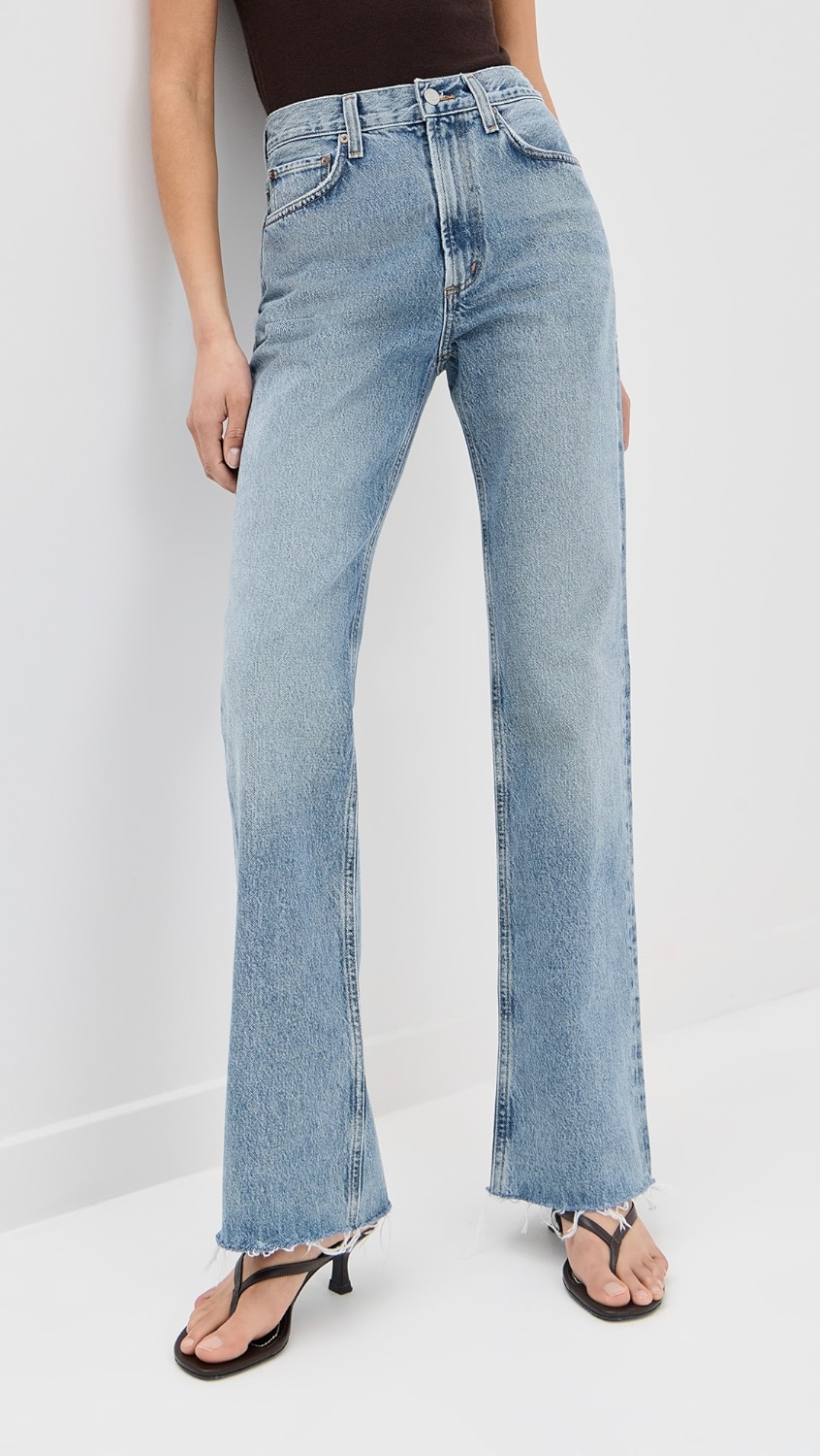 Light blue flared jeans with distressing on a model.