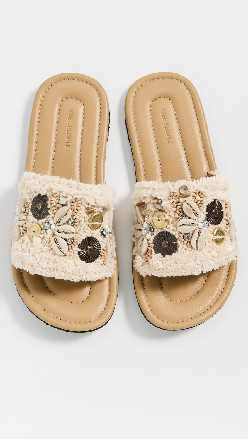 Tan slip on sandals with shells on the cream strap.