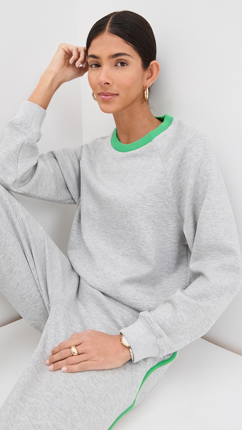 Grey crewneck with bright green trim on a model.