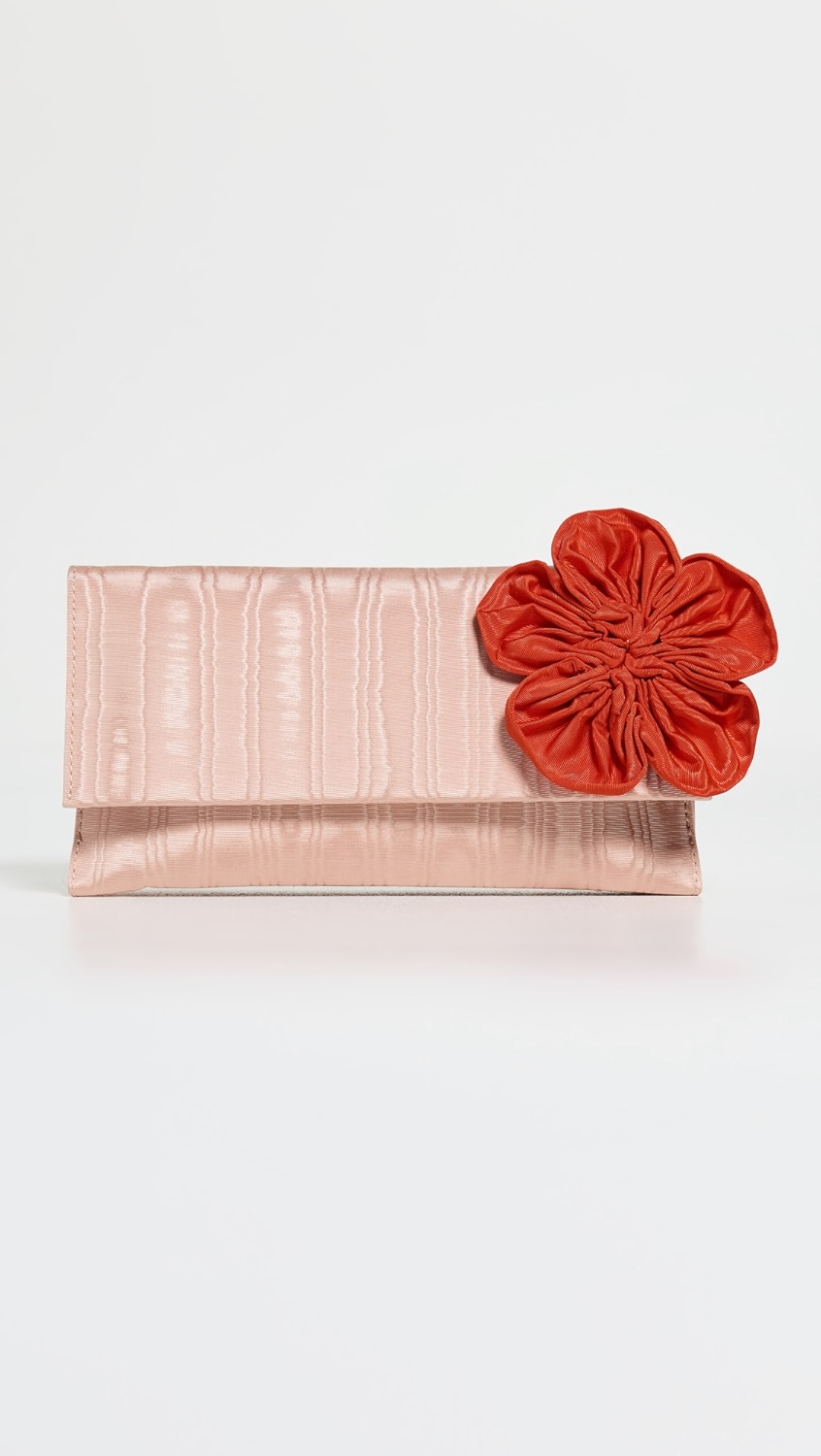 Shiny light pink clutch with a red scrunchy flower on the side.