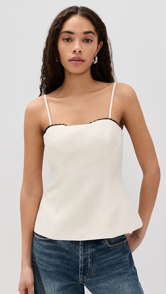 Off white spaghetti strap cami with black lace detail on a model.