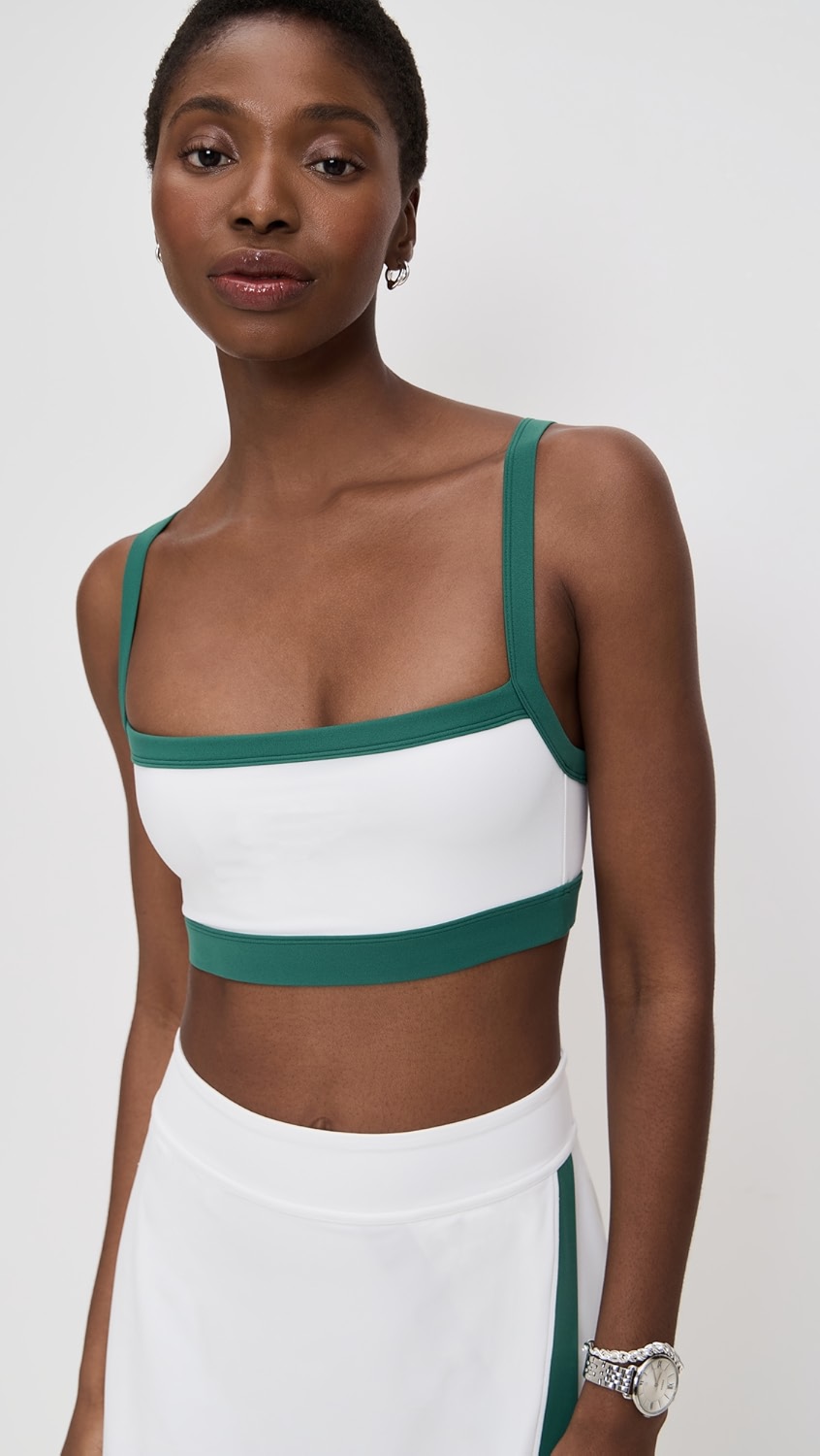 White sports bra with dark green trim on a model.