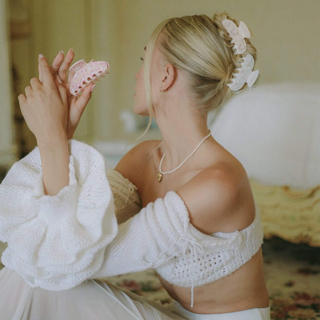 Holding and wearing pink and white floral Emi Jay hair clips