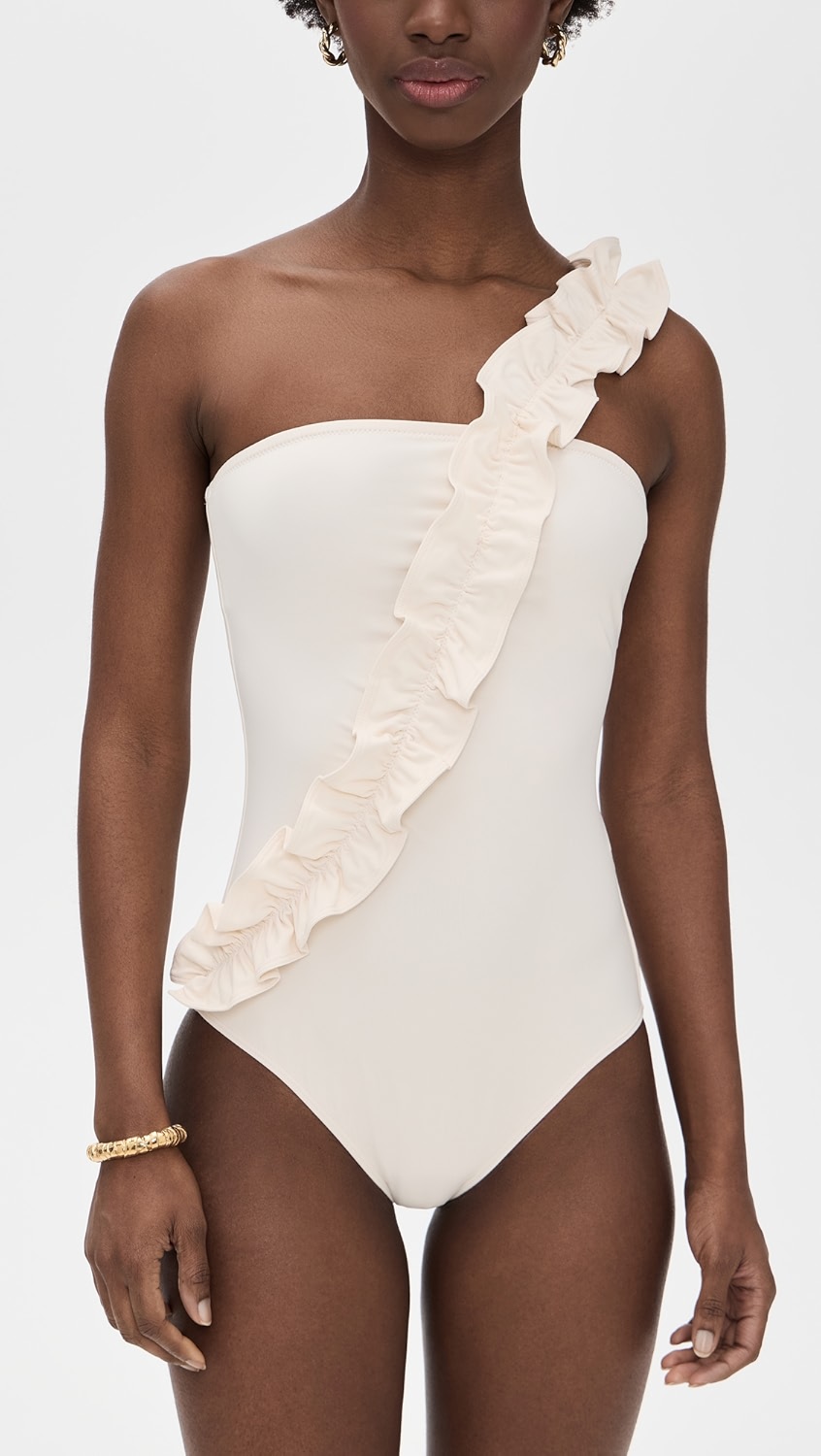 White one piece swimsuit with a ruffle strap on a model.
