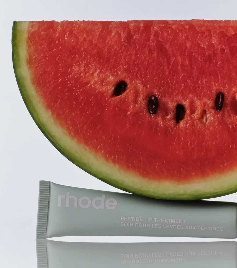 Rhode Watermelon Slice Peptide Lip Treatment under a watermelon slice with a gray background