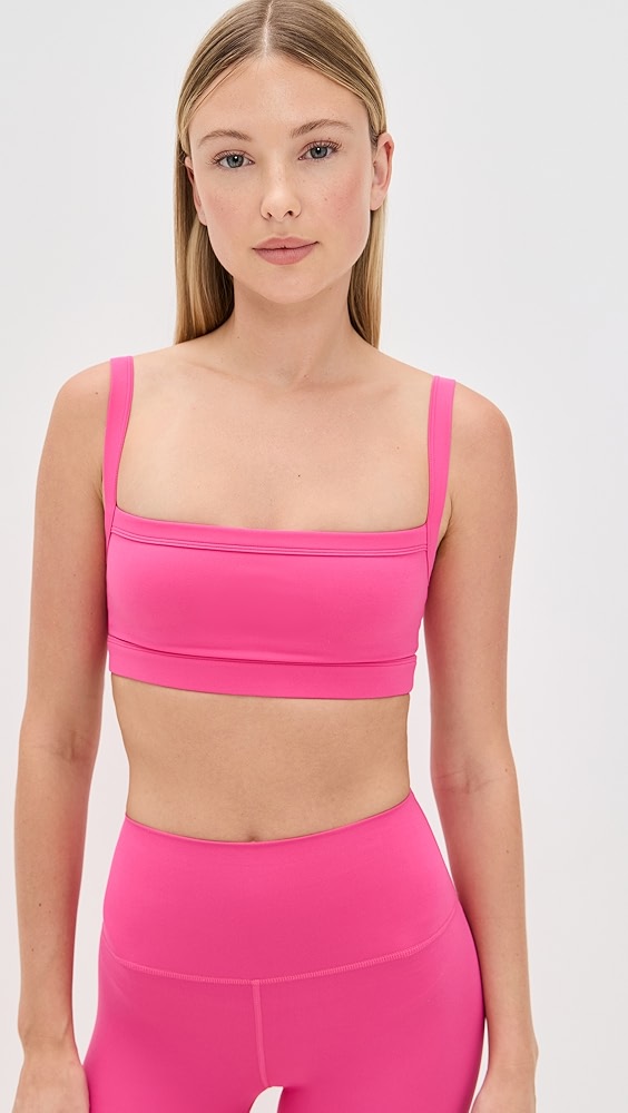 Bright pink sports bra on a model, which is one of the trendy activewear pieces.